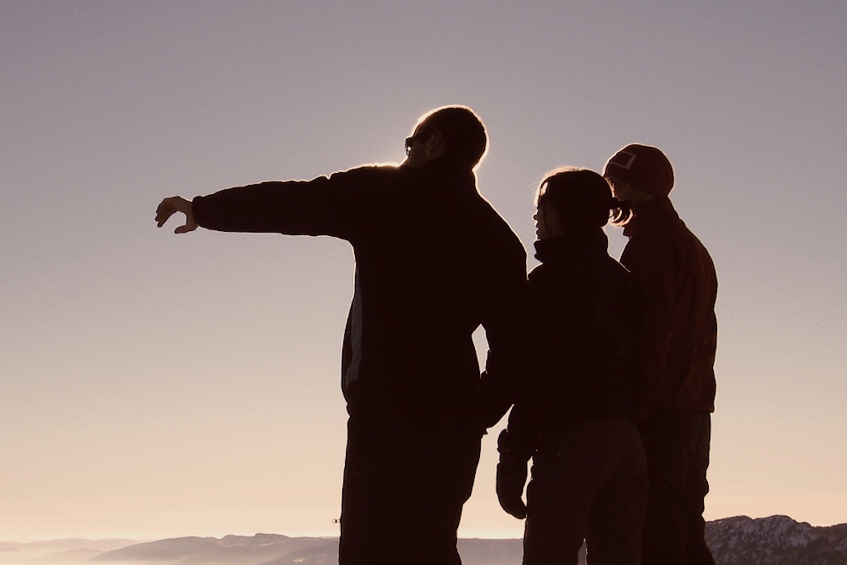 Ein Mann weist 2 anderen Personen den Weg.